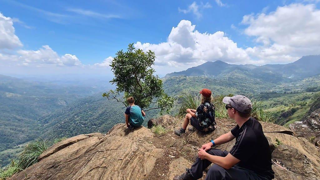 Voyageurs assis au sommet d'un rocher face aux collines du pays du thé, Sri Lanka